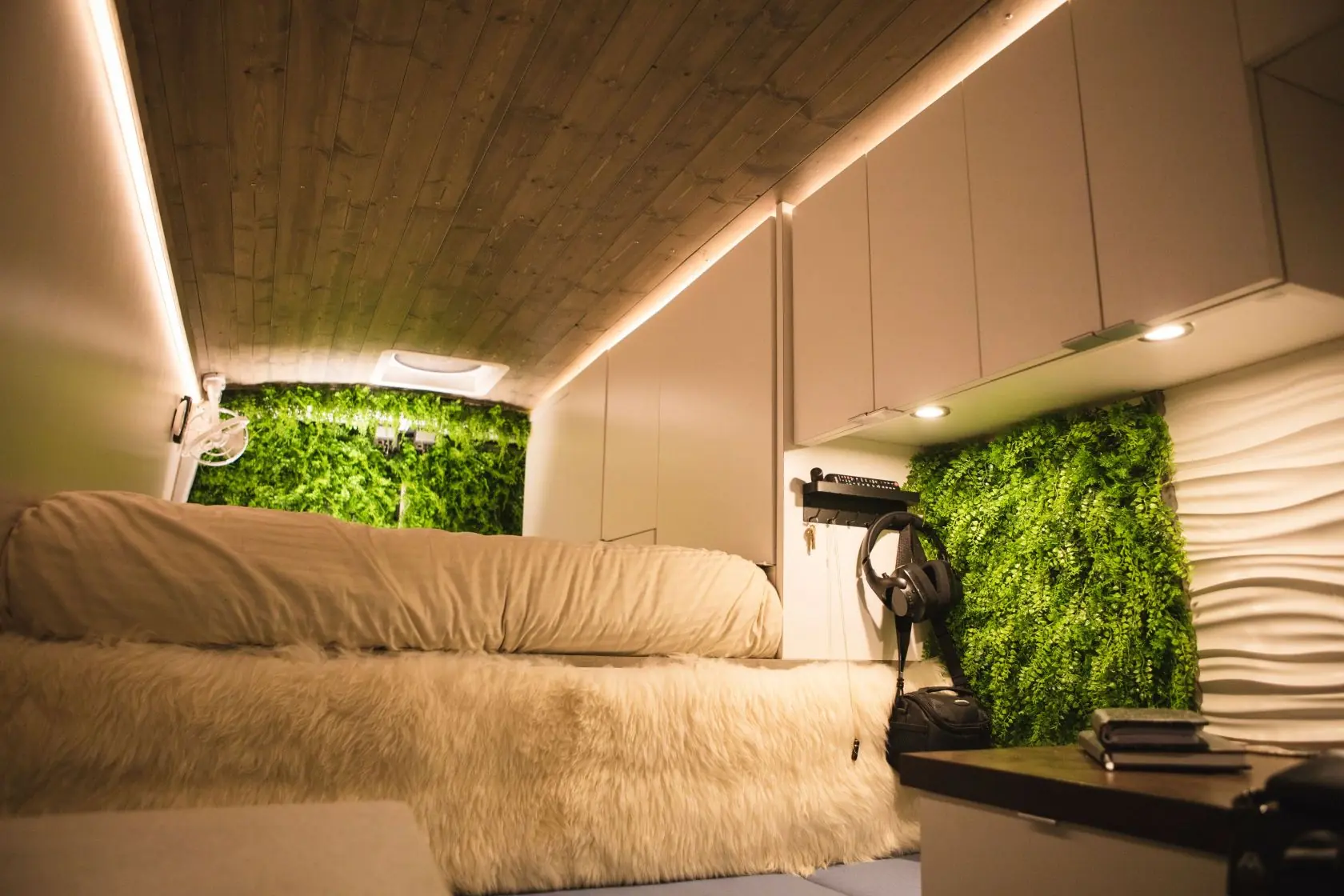 Inside the van at night: the bed, plant walls, and warm light strips