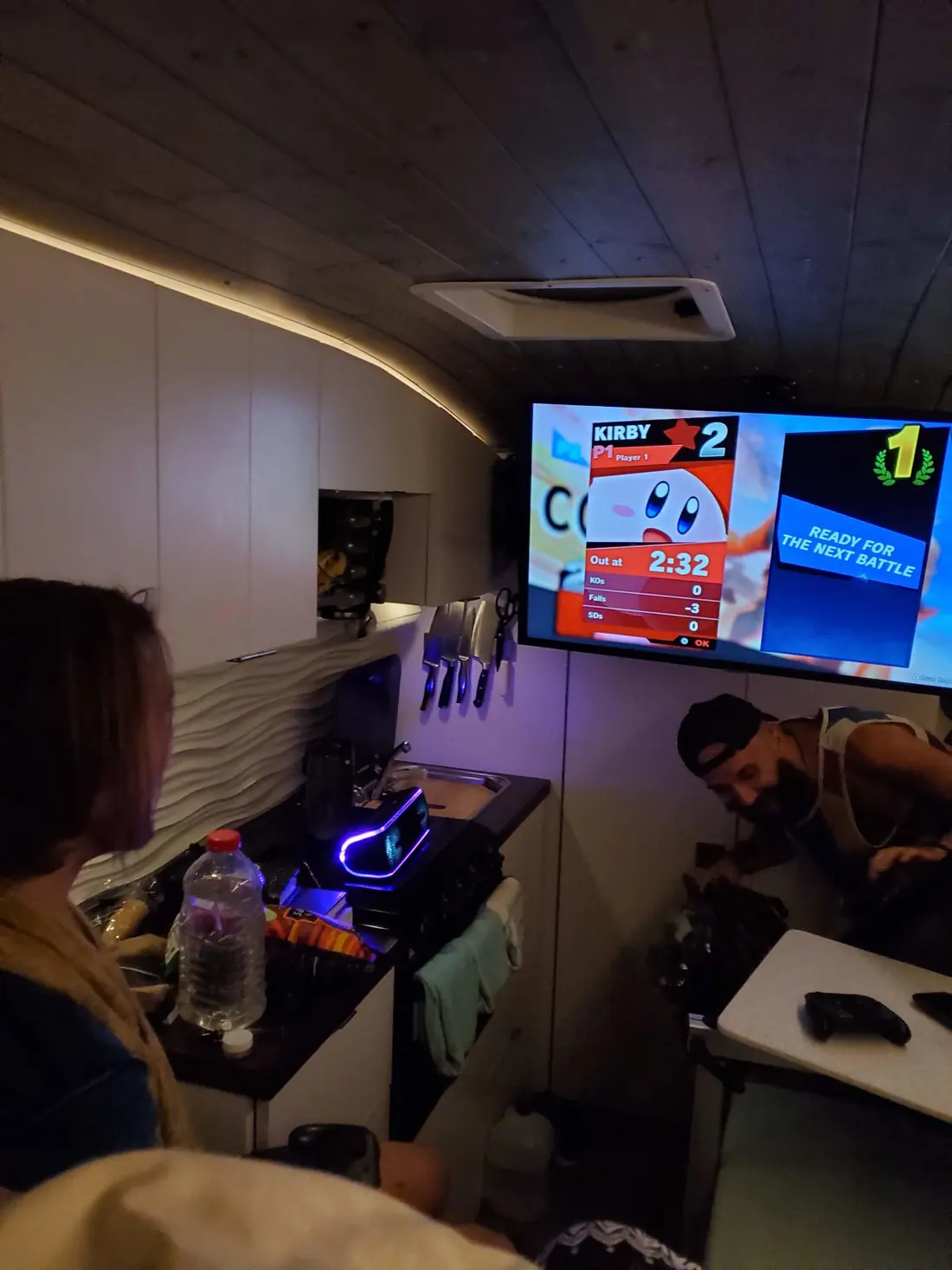 Friends playing Smash Bros on the TV inside the van